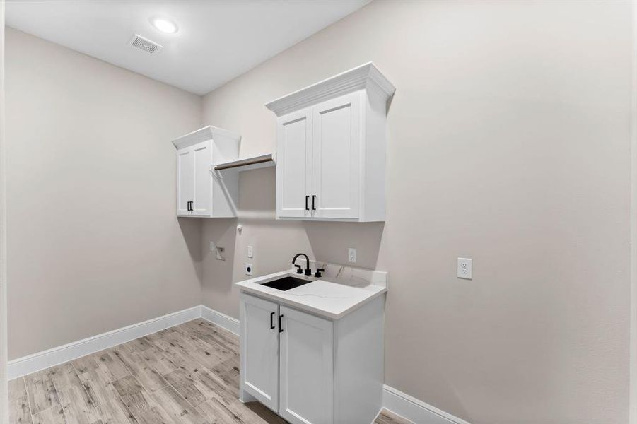 Large utility room includes sink and and custom cabinetry