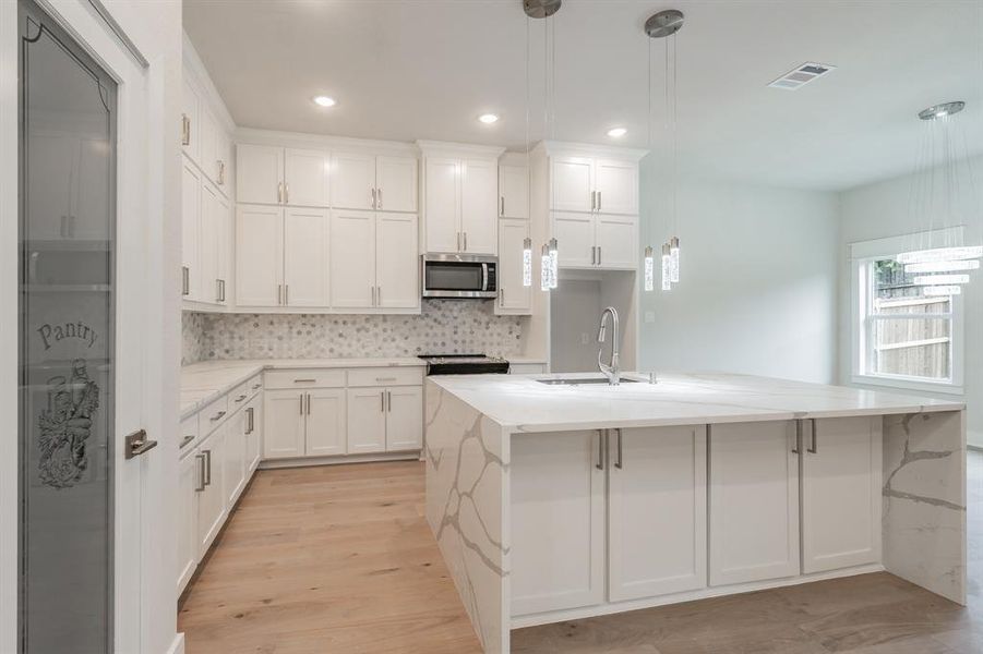 Kitchen with decorative backsplash, light stone counters, white cabinets, pendant lighting, and recessed lighting