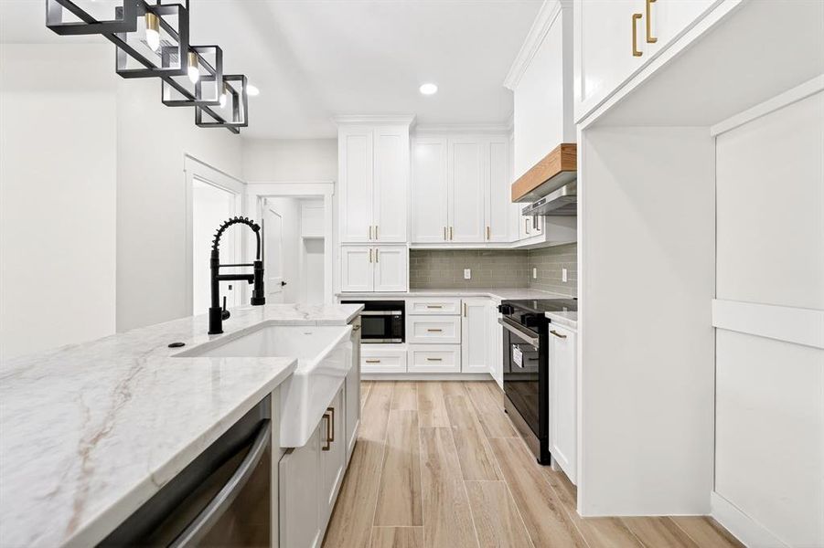 Kitchen featuring a large island with a farmhouse sink and matte black gooseneck faucet Kitchen featuring a large island with a farmhouse sink and matte black gooseneck faucet