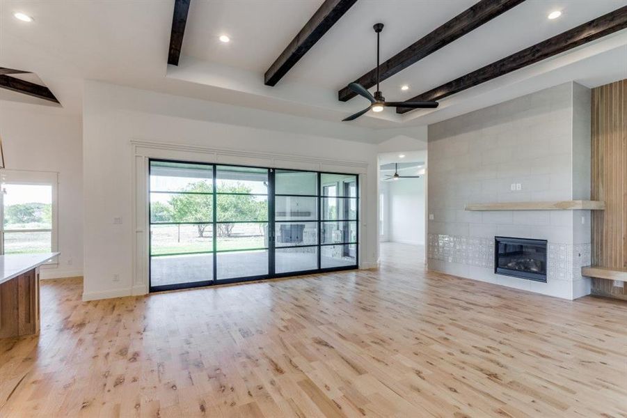 Living room with light wood-type flooring, a fireplace, ceiling fan, and plenty of natural light