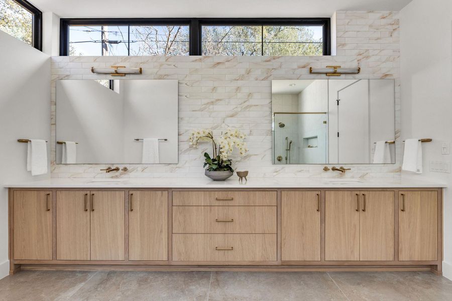 Bathroom with a shower stall, double vanity, and decorative backsplash