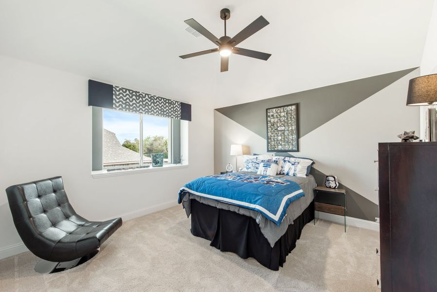Bedroom with vaulted ceiling, ceiling fan, geometric accent wall, and blue bedding on a full-size bed Bedroom with vaulted ceiling, ceiling fan, geometric accent wall, and blue bedding on a full-size bed