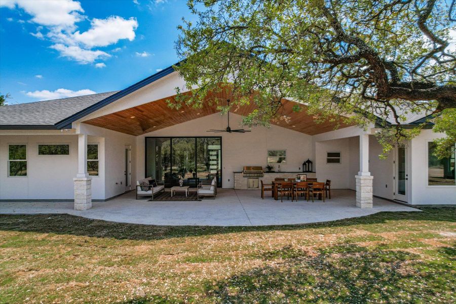 Rear view of property with a lawn, a patio area, stucco siding, and an outdoor living / dining area