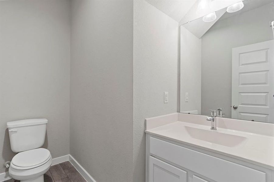 The half bathroom boasts tile flooring, light countertops, a stylish mirror, and modern lighting fixtures and finishes, offering both convenience and elegance for your guests.