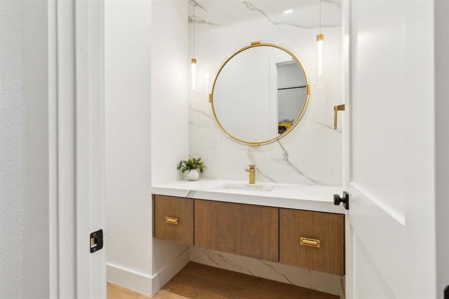 Designer powder bath with statement mirror, custom vanity, and elegant marble finishes.