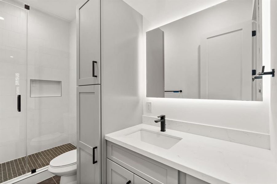 Additional secondary bathroom features walk-in shower, modern lighting, extended quartz countertop and plenty of storage.