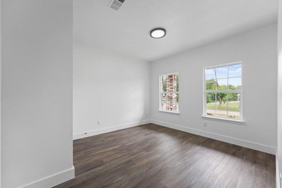 Bright interior space featuring wood-finish flooring, white baseboards, and two double-hung windows Bright interior space featuring wood-finish flooring, white baseboards, and two double-hung windows