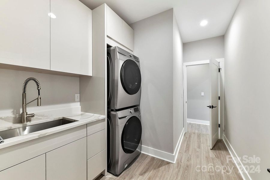 Large Laundry Room with quartz surround sink, plenty of cabinetry for storage & LVP floors!