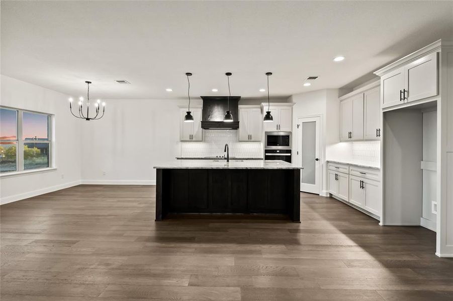 Kitchen with decorative backsplash, pendant lighting, white cabinetry, a kitchen island with sink, and recessed lighting