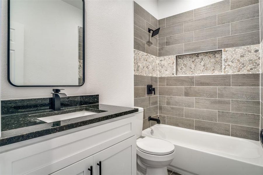 Full bathroom with toilet, tiled shower / bath combo, and vanity