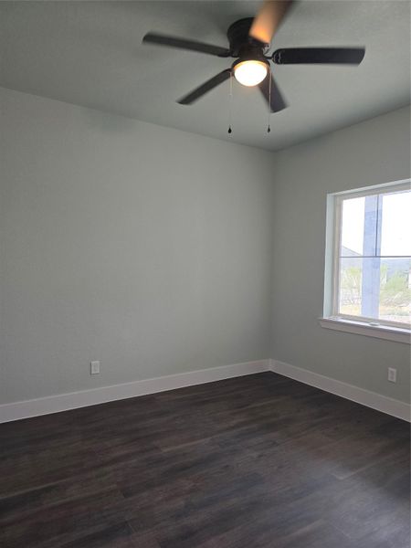 Unfurnished room with dark wood-style flooring and a ceiling fan