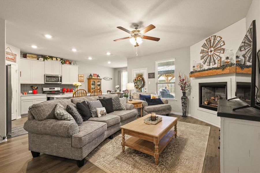Living area with a fireplace, a ceiling fan, recessed lighting, and wood finished floors Living area with a fireplace, a ceiling fan, recessed lighting, and wood finished floors