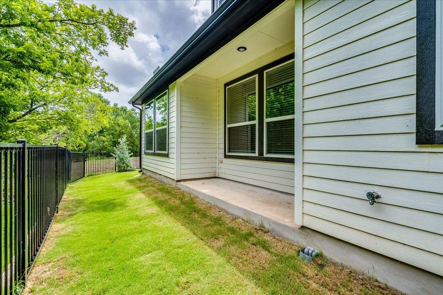 An inviting backyard patio offers a private space for outdoor relaxation, enclosed by a sturdy fence.