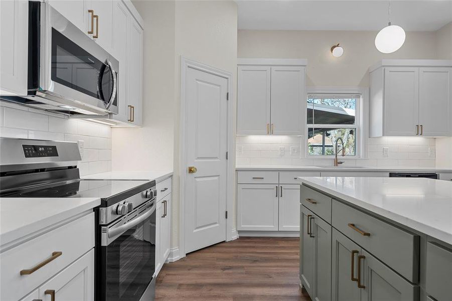 Kitchen featuring stainless steel appliances, decorative light fixtures, and white cabinetry Kitchen featuring stainless steel appliances, decorative light fixtures, and white cabinetry