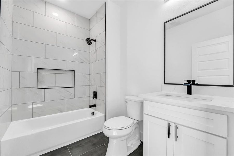 Full bathroom with tile patterned flooring, tiled shower / bath combo, toilet, and vanity