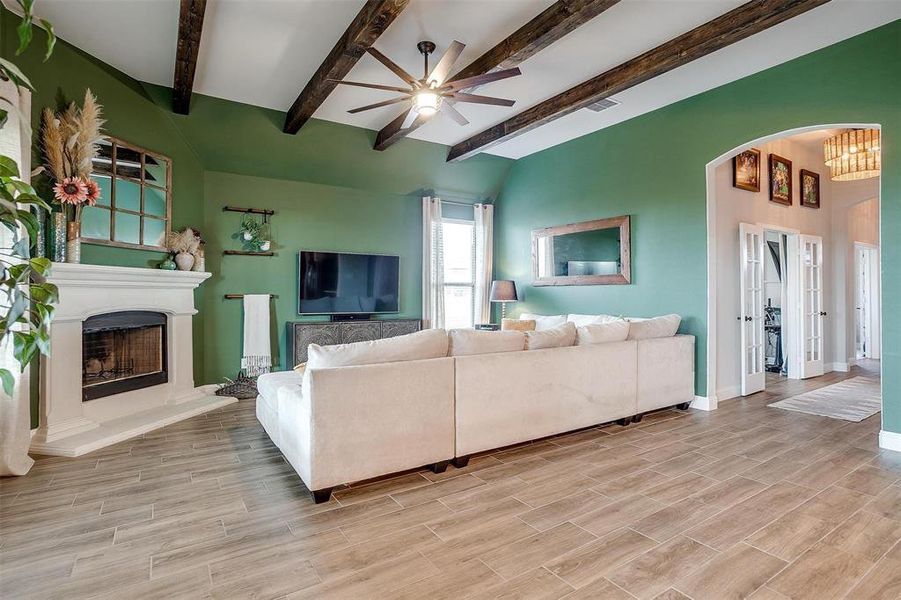 Living room with beamed ceiling, ceiling fan, and light hardwood / wood-style flooring