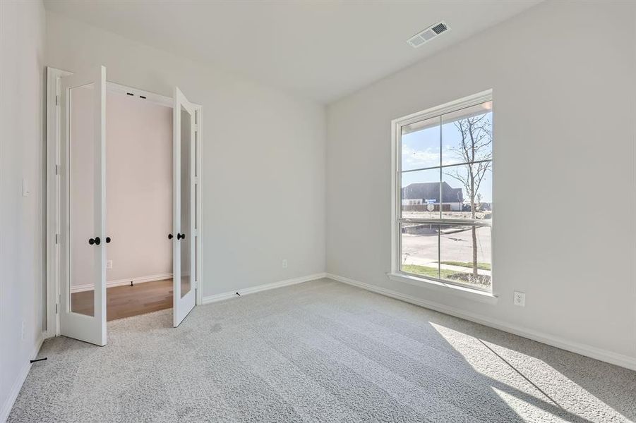 Unfurnished bedroom with french doors and light colored carpet