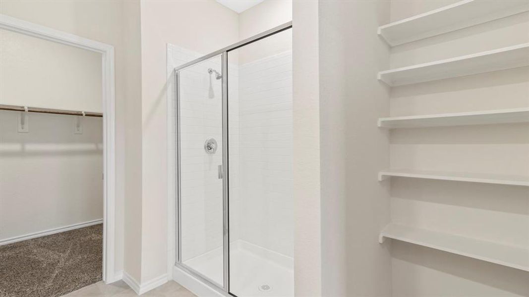 Glass-enclosed shower with white tiled walls and a chrome showerhead