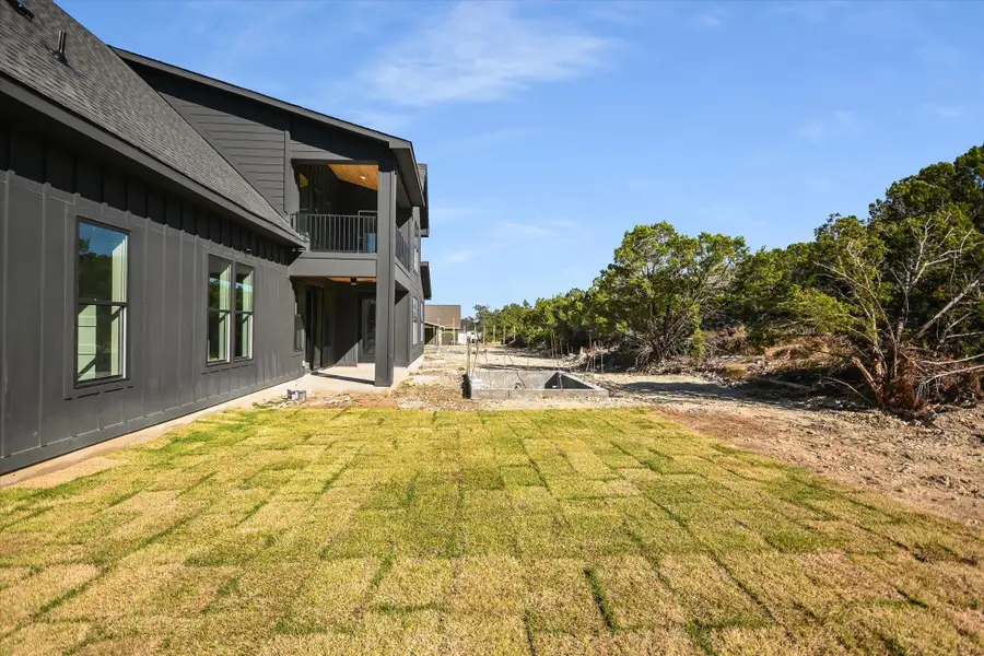 View of grassy yard with a balcony and a patio area