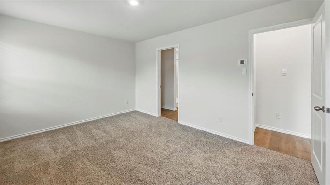 Spacious room featuring neutral carpeting, white baseboards, and recessed lighting