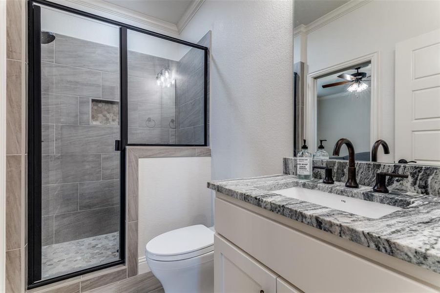 Bathroom featuring crown molding, vanity, a shower stall, and ceiling fan