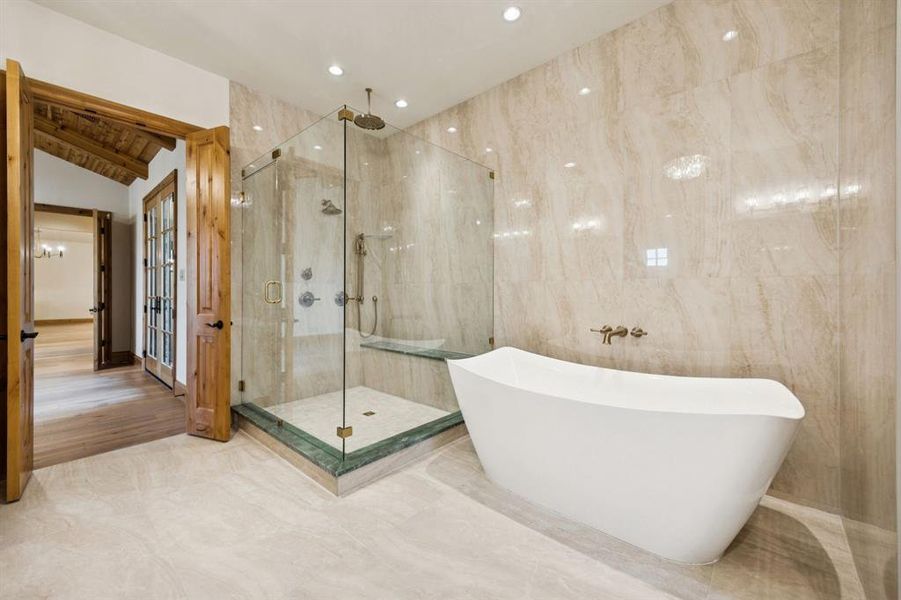 Bathroom with a freestanding bath, a marble finish shower, and lofted ceiling