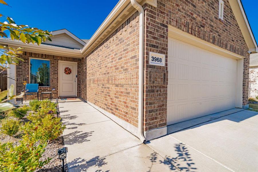 Entrance to property with a garage, brick siding, and driveway