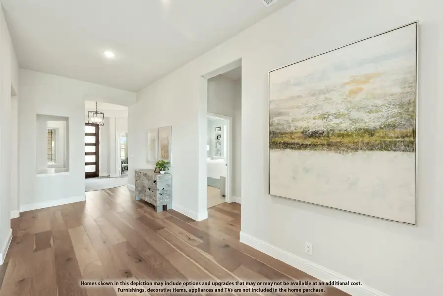 Hallway with hardwood floors, white walls, large wall art, and view toward front entry with pendant light. Hallway with hardwood floors, white walls, large wall art, and view toward front entry with pendant light.