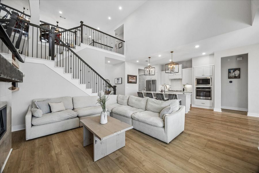 The spacious family room features soaring ceilings and an open layout that connects seamlessly to the kitchen, with views of the staircase and second floor above.
