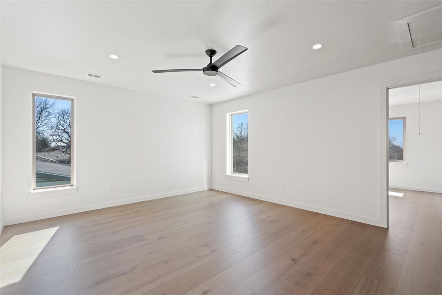 Empty room featuring plenty of natural light, attic access, visible vents, and light wood finished floors