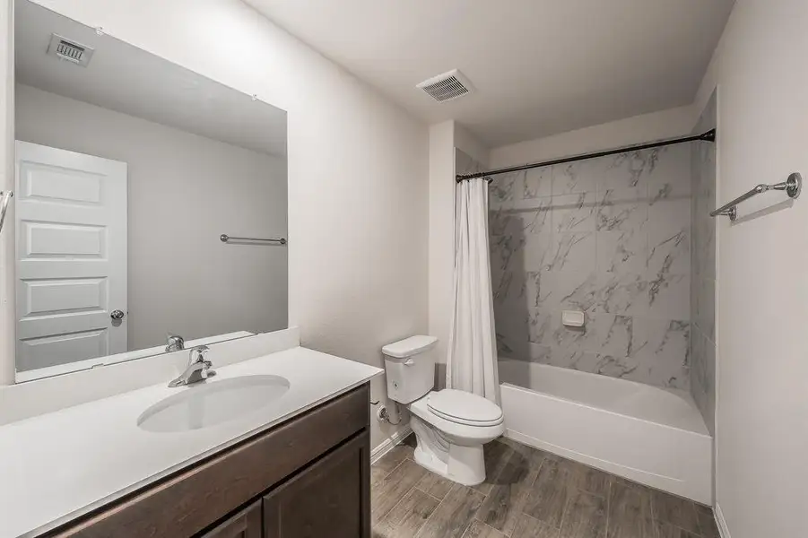 Full bathroom with shower / bath combo with shower curtain, vanity, and wood finish floors Full bathroom with shower / bath combo with shower curtain, vanity, and wood finish floors