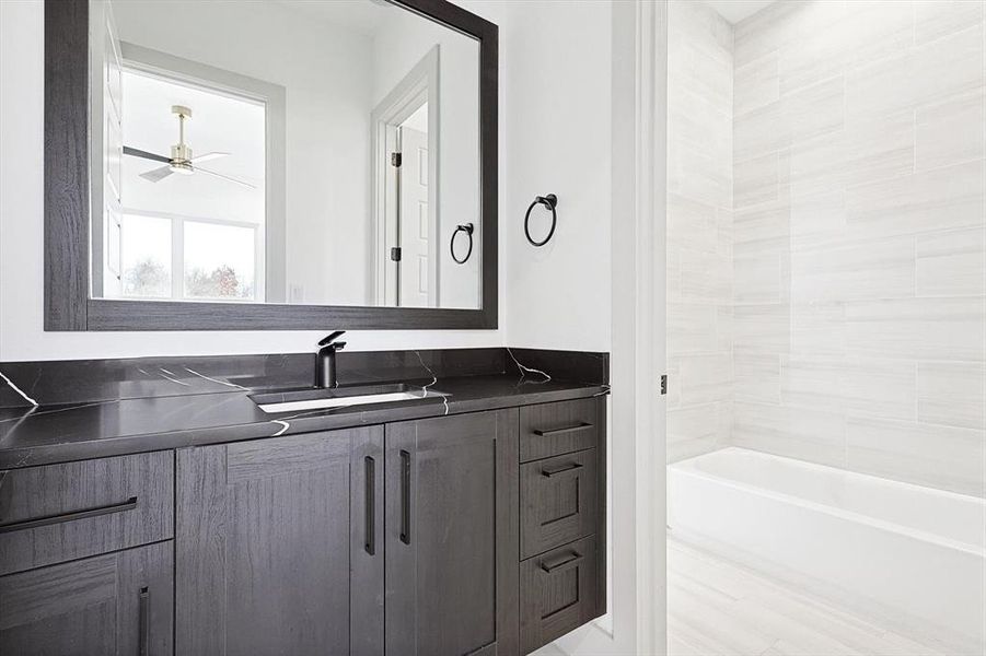 Bathroom with bathing tub / shower combination, ceiling fan, and vanity