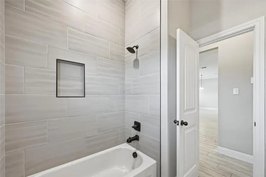 Full bath featuring shower / bathtub combination and light wood finished floors Full bath featuring shower / bathtub combination and light wood finished floors