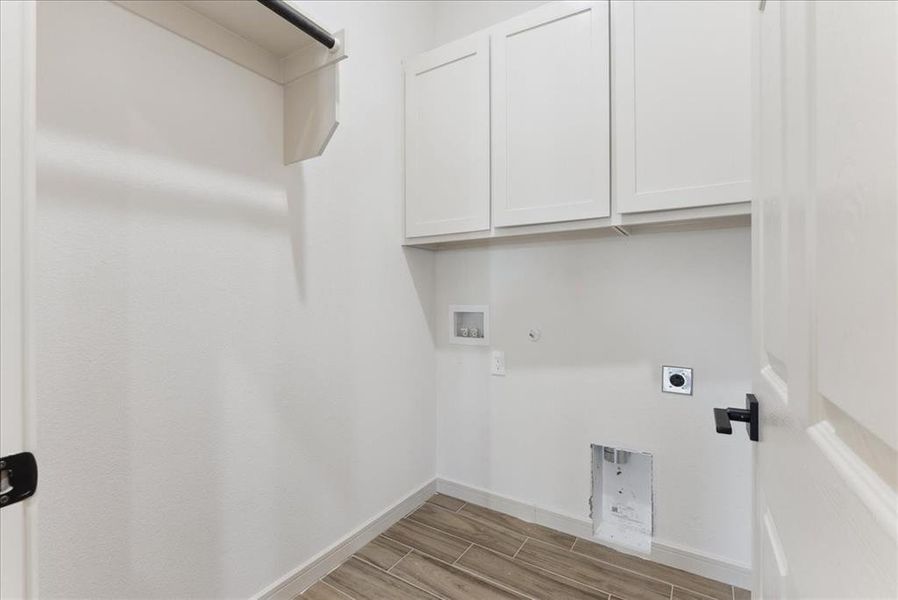 Clothes washing area with cabinets, hookup for a gas dryer, hookup for a washing machine, light hardwood / wood-style flooring, and hookup for an electric dryer