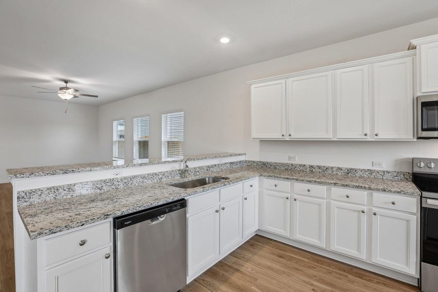 Chef ready kitchen with energy-efficient Whirlpool® kitchen appliances, sparkling granite countertops, 36 inch upper wood cabinets with crown molding detail