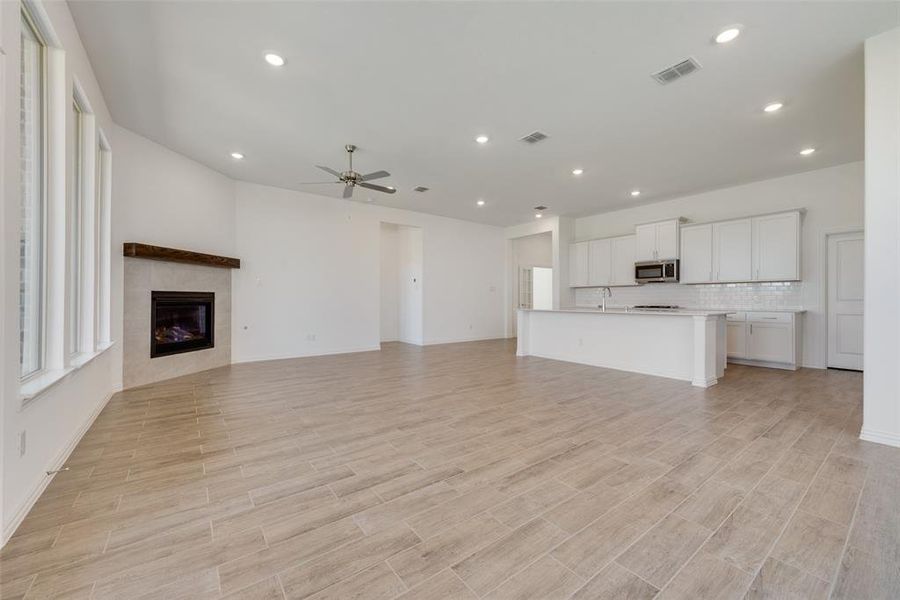 Unfurnished living room with a fireplace, light hardwood / wood-style flooring, ceiling fan, and sink