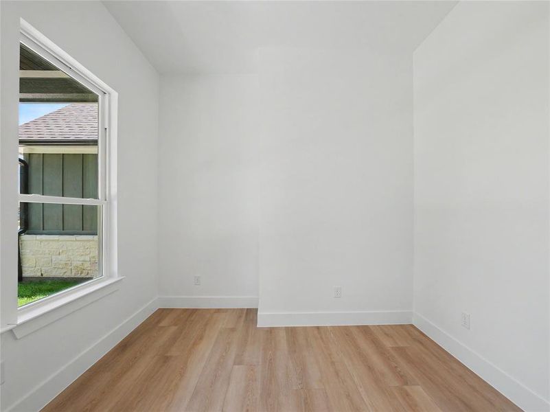 Room featuring white walls, wood-finish flooring, and white baseboards Room featuring white walls, wood-finish flooring, and white baseboards