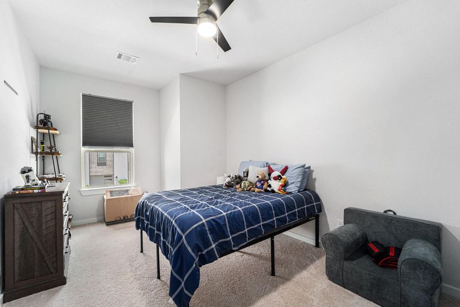Light-filled secondary bedroom with neutral tones and plush carpet.