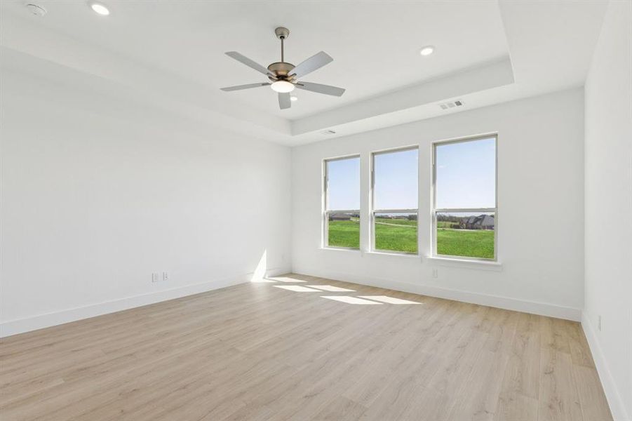 Spare room with light wood-type flooring, a tray ceiling, recessed lighting, and ceiling fan