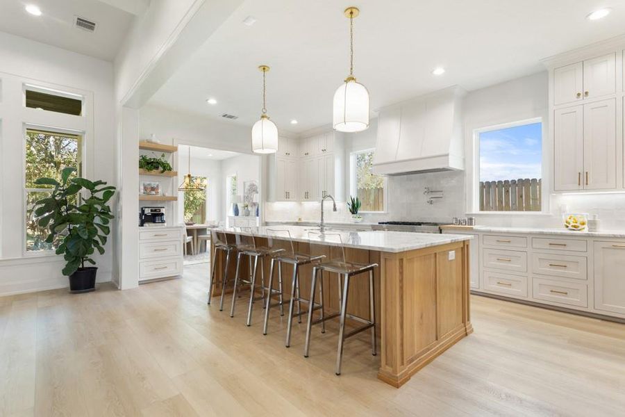 Kitchen with healthy amount of natural light, decorative light fixtures, a breakfast bar, an island with sink, and recessed lighting