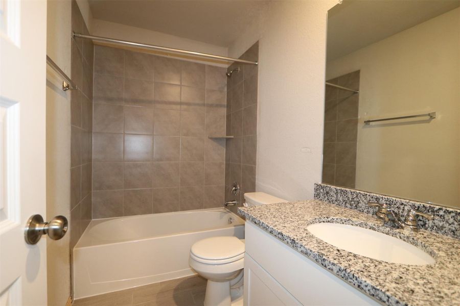 Full bathroom featuring hardwood / wood-style floors, toilet, vanity, and tiled shower / bath