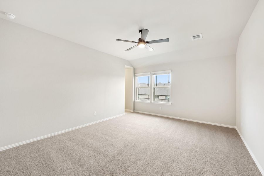 Empty bedroom with vaulted ceiling, ceiling fan, carpet flooring, and a double window Empty bedroom with vaulted ceiling, ceiling fan, carpet flooring, and a double window