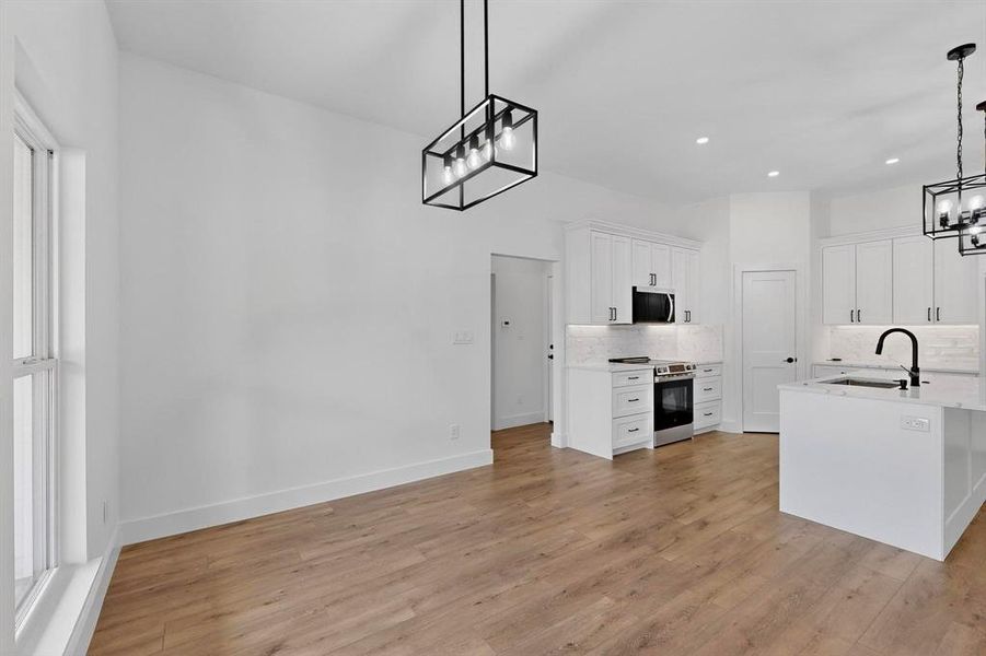 Kitchen featuring a chandelier, white cabinetry, tasteful backsplash, stainless steel range with electric stovetop, and recessed lighting