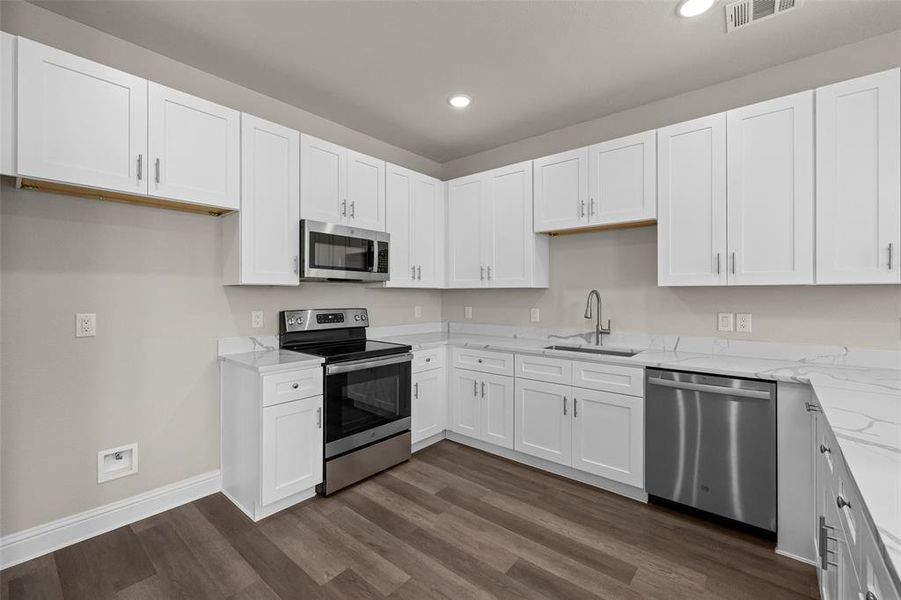 Kitchen featuring dark wood-type flooring, sink, white cabinetry, and stainless steel appliances