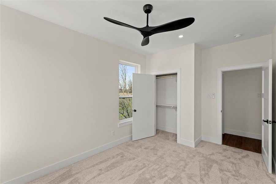 Unfurnished bedroom with light carpet, a ceiling fan, a closet, and recessed lighting
