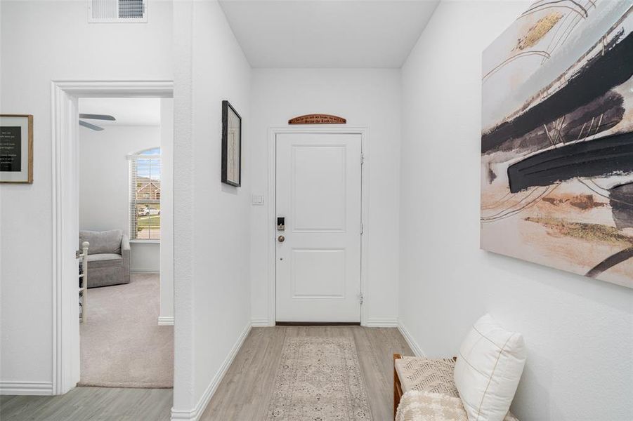 Entryway featuring light-colored flooring, a white door, and an overhead vent
