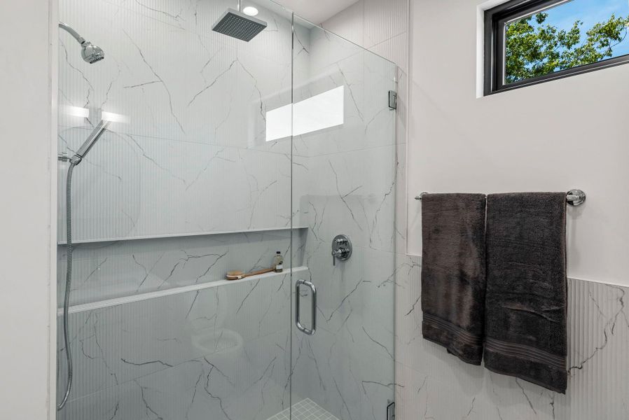 Primary Bathroom featuring a marble finish spa shower with 3 shower heads Primary Bathroom featuring a marble finish spa shower with 3 shower heads