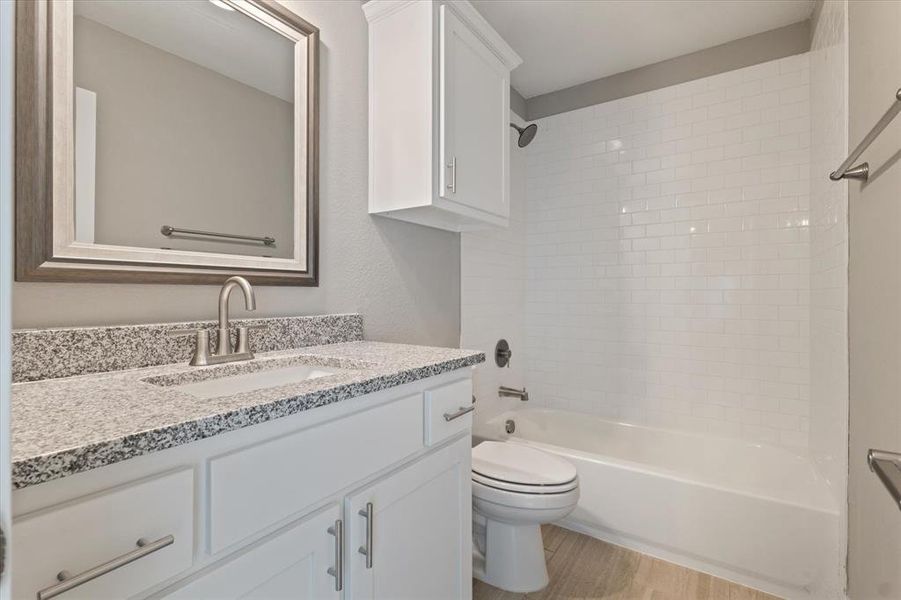 Full bathroom featuring hardwood / wood-style floors, vanity, toilet, and tiled shower / bath Full bathroom featuring hardwood / wood-style floors, vanity, toilet, and tiled shower / bath