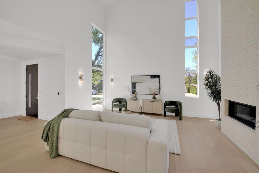 Living room with 24' high ceiling, light wood-style floors, and floor to ceiling brick fireplace