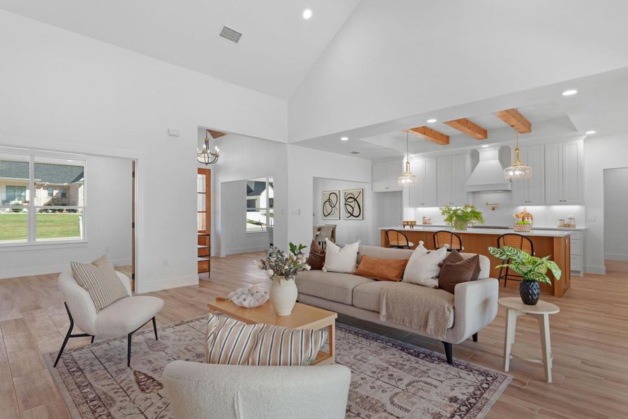 Living room with light wood-type flooring, suspended lighting, and vaulted ceiling Living room with light wood-type flooring, suspended lighting, and vaulted ceiling